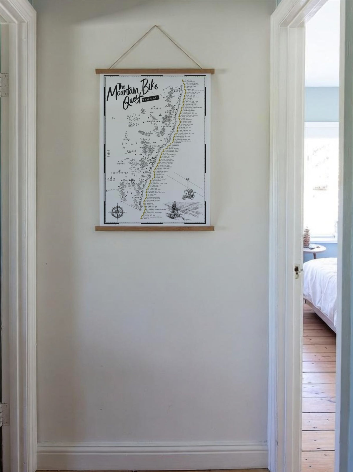 NSW & ACT Mountain Bike Quest scratch map displayed in a wooden hanging frame in a hallway
