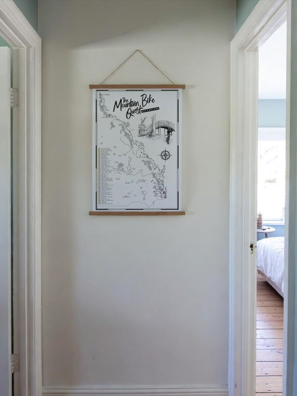 Queensland Mountain Bike Quest scratch map displayed in a wooden hanging frame in a hallway