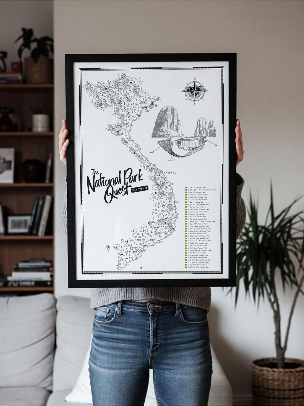 Person holding a framed Vietnam National Parks Quest scratch map in a home