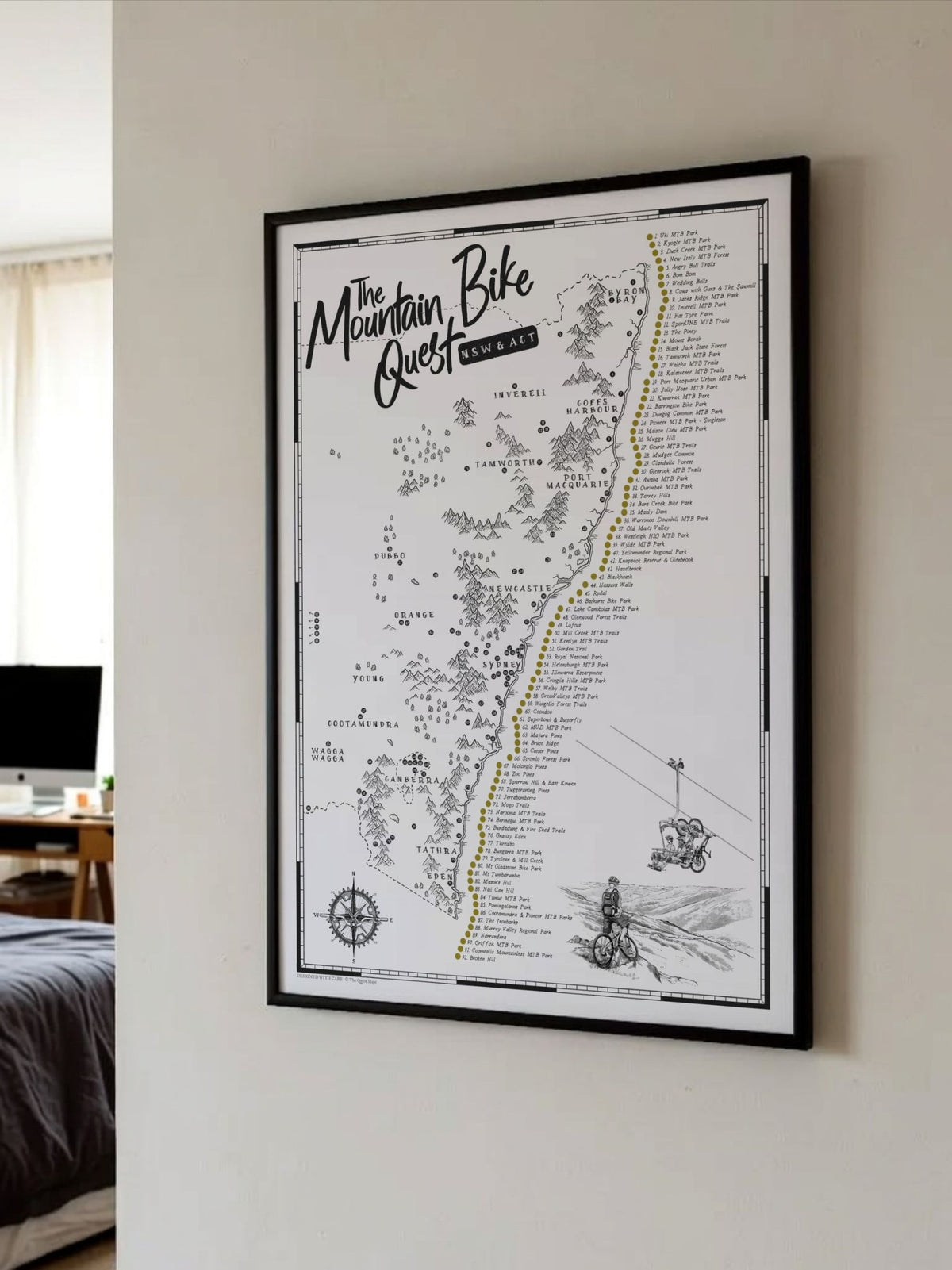 Framed NSW & ACT Mountain Bike Quest scratch map displayed on a bedroom wall