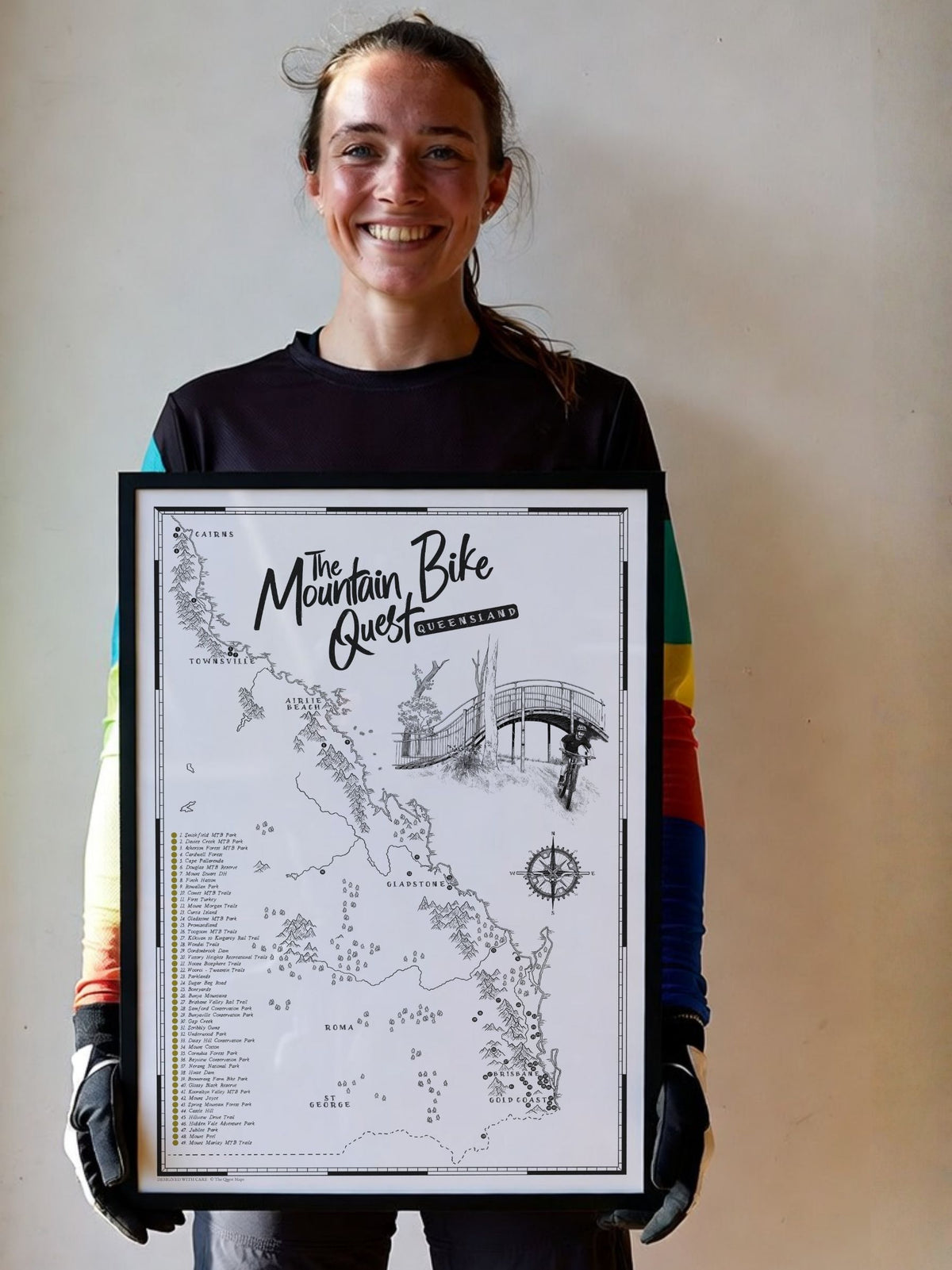 Mountain biker holding a framed Queensland Mountain Bike Quest scratch map