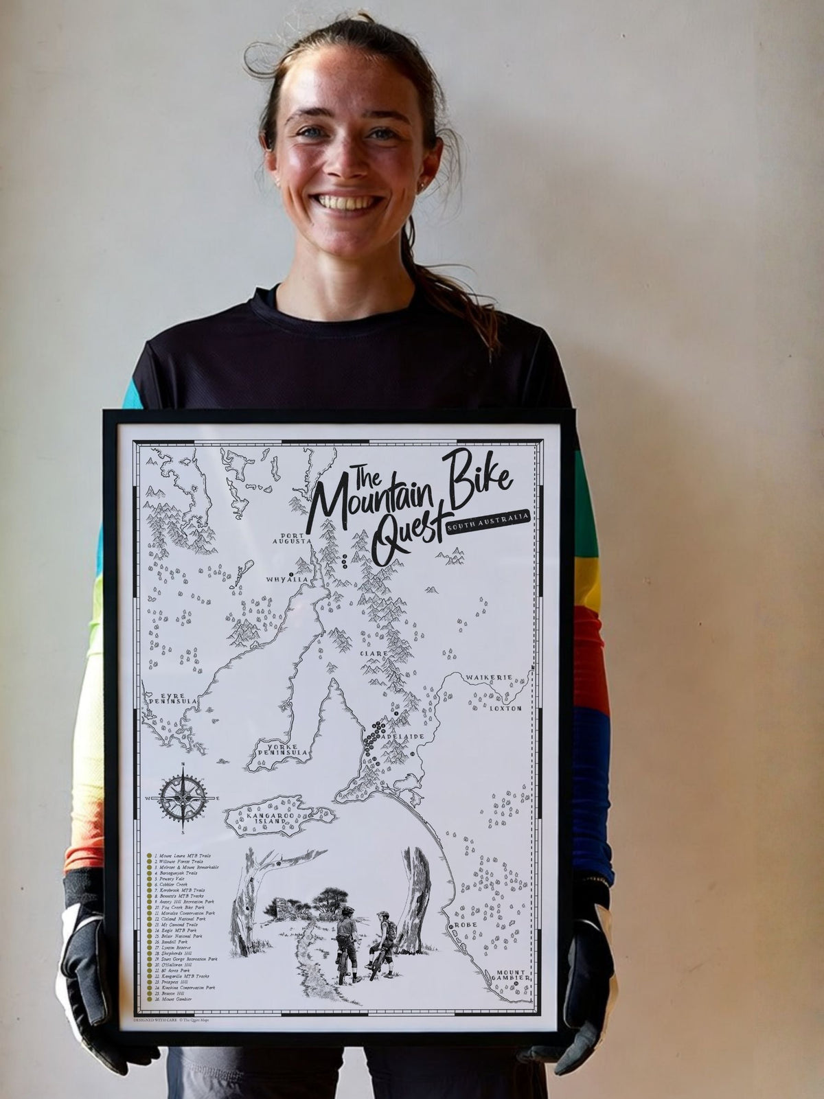 Woman holding a framed South Australia Mountain Bike Quest scratch map